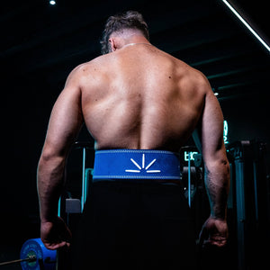 Man wearing navy blue Trackfie lifting belt standing in the gym with back turned