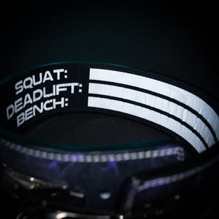 Inside of a purple Trackfie lifting belt where you can see the text 'squat, deadlift, bench' in white