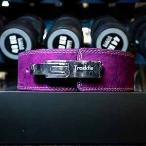 Purple Trackfie lever belt in front of dumbbells in a gym