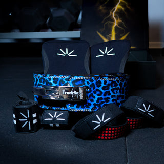Blue leopard Trackfie bundle consisting of lever belt, knee sleeves, wrist wraps, and lifting straps assembled in a gym