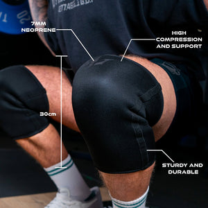 Close-up of a man squatting with black Unlisted Strength knee sleeves and illustrations highlighting specifications