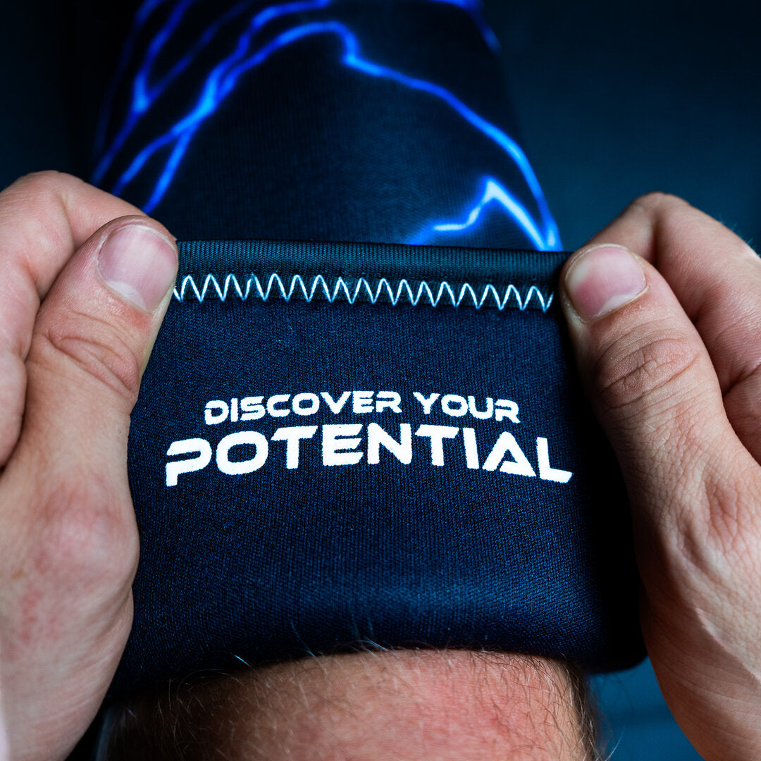 Blue Unlisted Strength knee sleeves being applied to legs with 'discover your potential' text on the inside