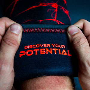 Red Unlisted Strength knee sleeves being applied to legs with 'discover your potential' text on the inside