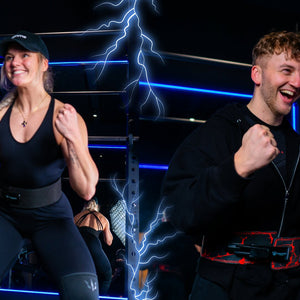 A woman and a man are cheering in a gym wearing lever belts and knee sleeves.