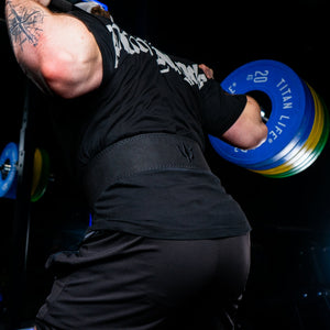 Man performing squats with a barbell and lifting belt in gym