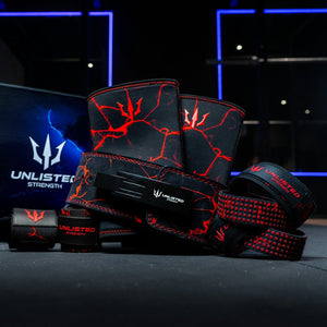Red Unlisted Strength bundle consisting of lever belt, knee sleeves, wrist wraps, and lifting straps assembled in front of an Unlisted Strength box in a gym