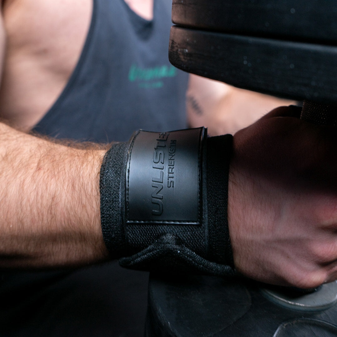 Close-up of black wrist wraps on a man sitting with dumbbells