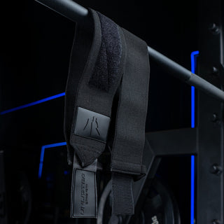 Black Unlisted Strength wrist wraps hanging down from barbell