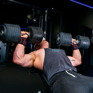 Man performing incline dumbbell press exercise with red wrist wraps in the gym