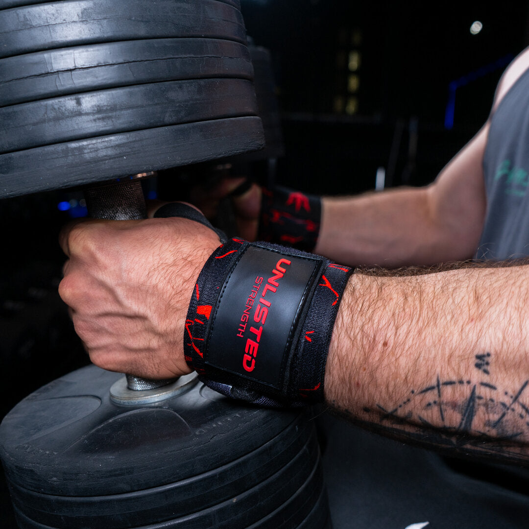 Close-up of red wrist wraps on a man sitting with dumbbells